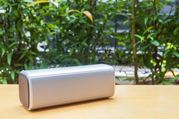 Wireless bluetooth portable speaker on wooden table in home garden