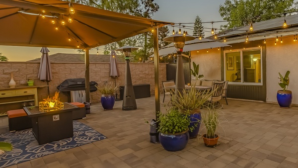 Cozy stone patio with string of lights over a covered seating and dining area