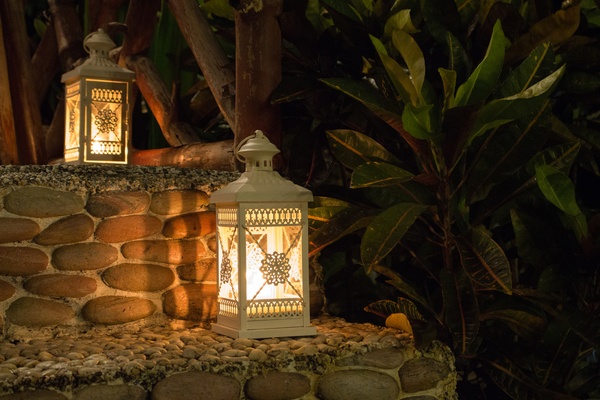 Two white lamps with burning flame on steps. Lantern in the evening garden.