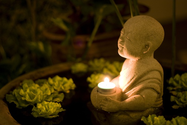 Serene garden pond with Buddha statue and candle 