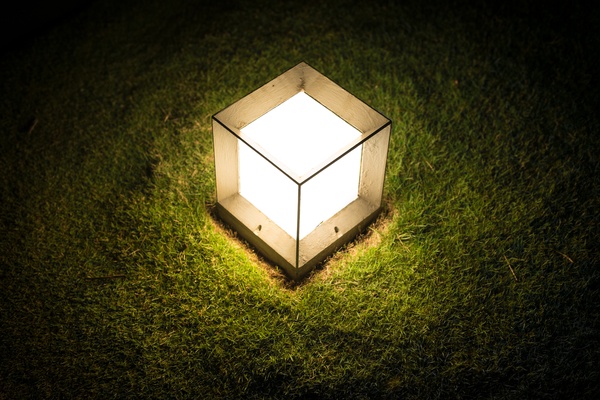 Lighting cube lantern on grass at night.