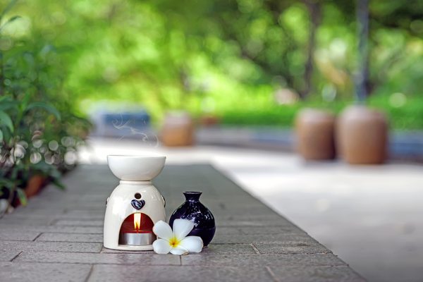 Aromatherapy oil burner with the frangipani flower and aromatherapy oil bottle in a garden