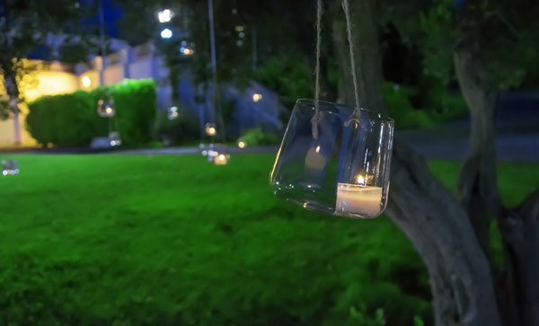 Candle in a glass hanging from a tree