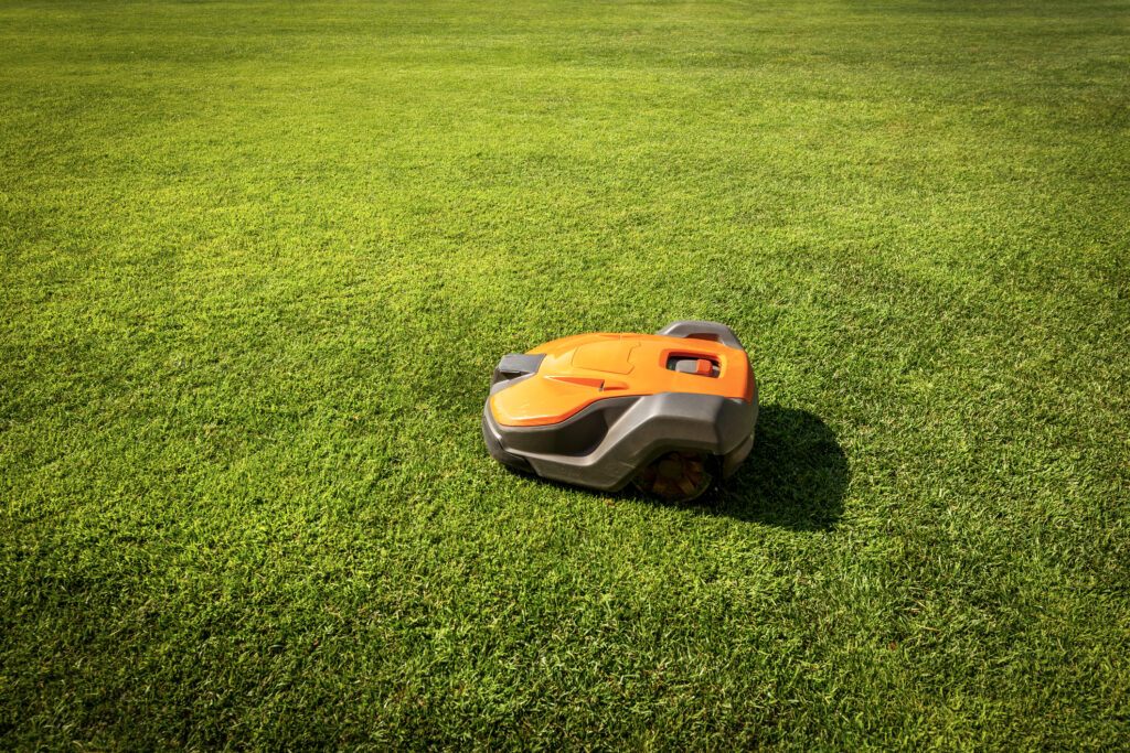 Automatic lawn mower robot moves on the green grass