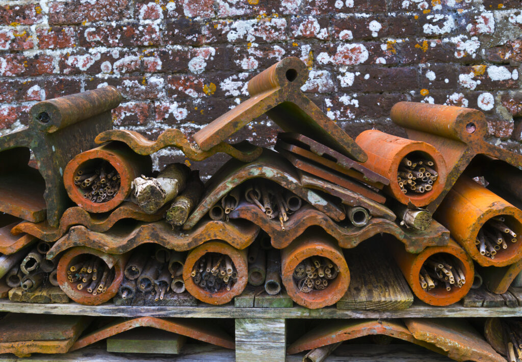 A bug hotel made from stacked terracotta drainage pipes, pots and roof tiles