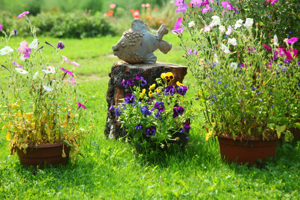 Flowers in pot and ceramic garden sculpture