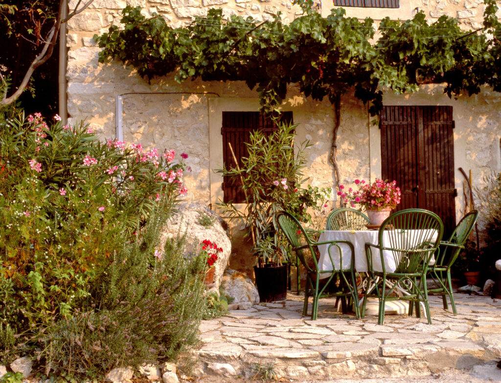 A quaint, pretty garden scene, with rustic patio furniture and ornamental flowers