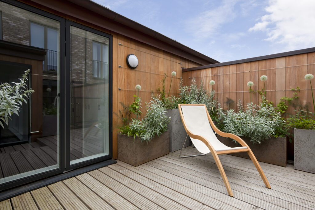 Simple attractive modern urban balcony garden with potted plants and reclining chair