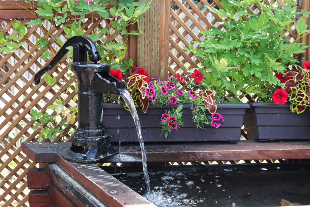 A water fountain in front of a lattice with annuals.