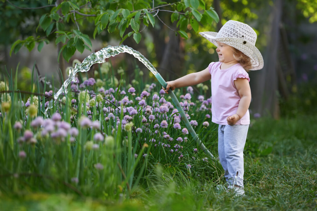 Little happy gardener watering onions.