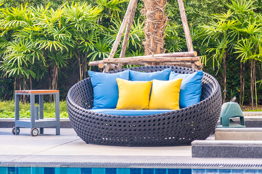 Wicker style cuddle chair by a pool in the garden