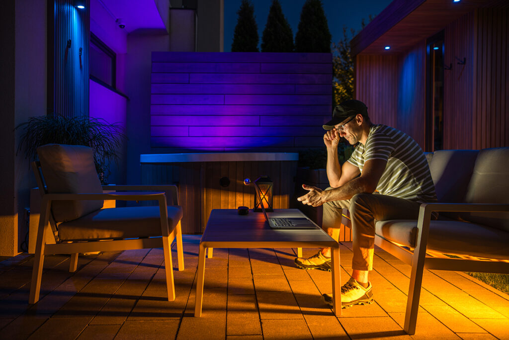 Man reads his phone in a modern garden seating area at night